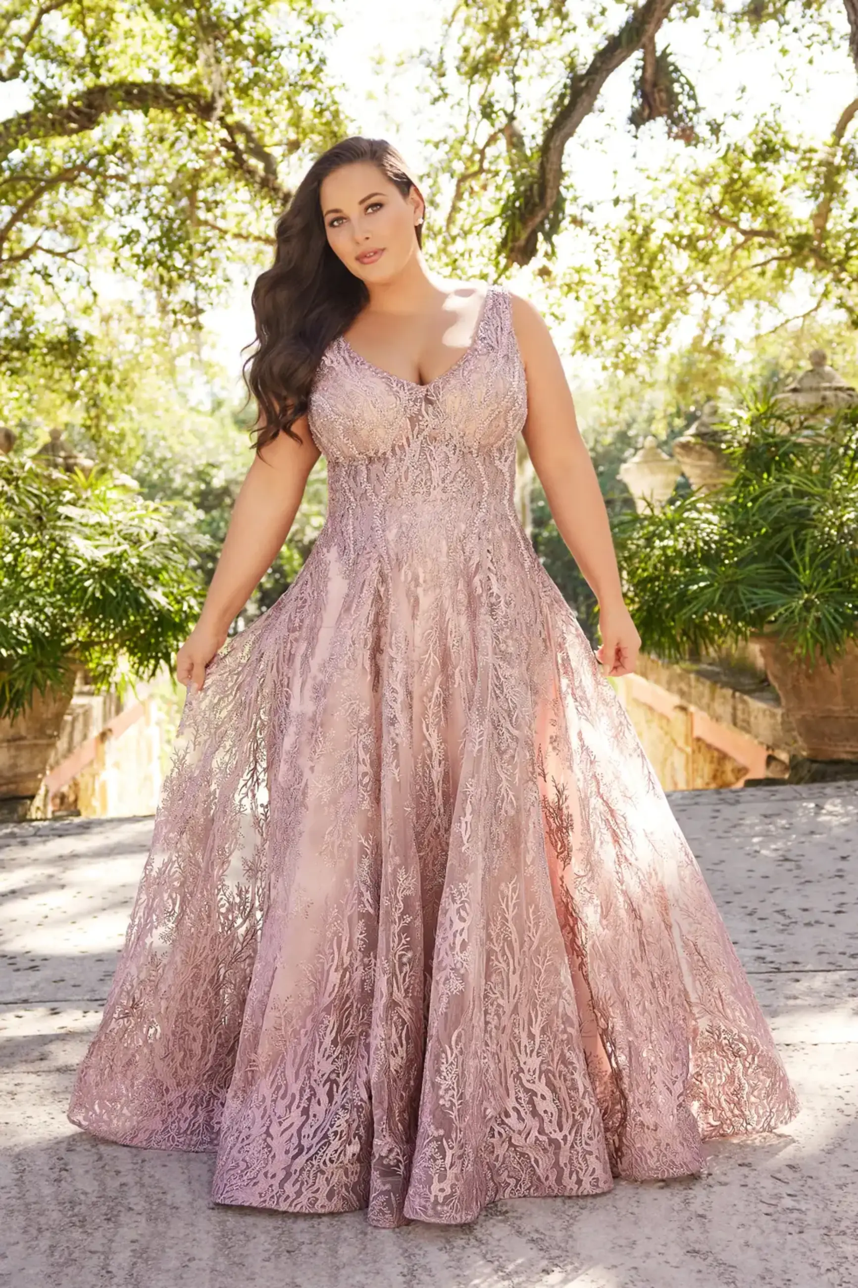 model is wearing a plus size light pink embroidered fit and flare mother of the bride gown