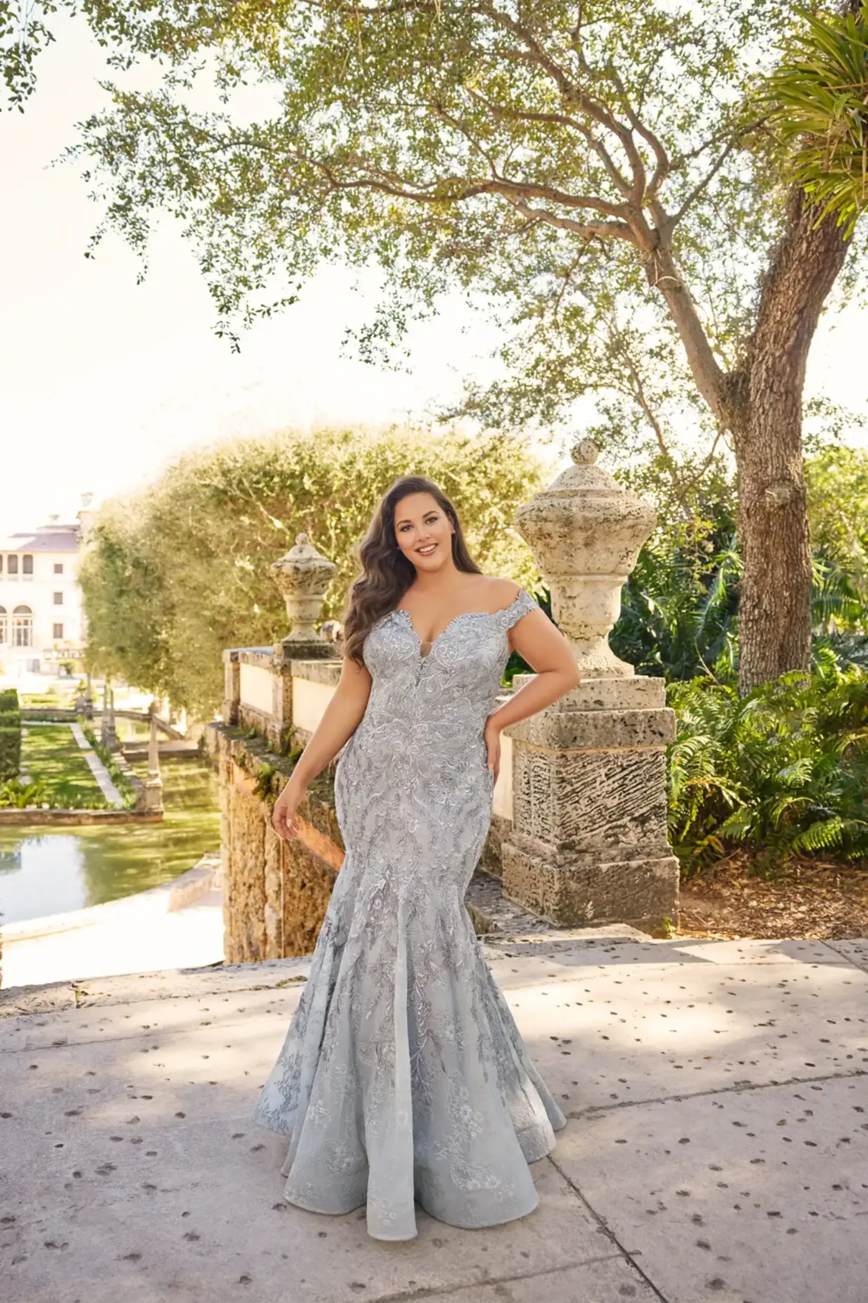 model is wearing a plus size mermaid mother of the bride gown