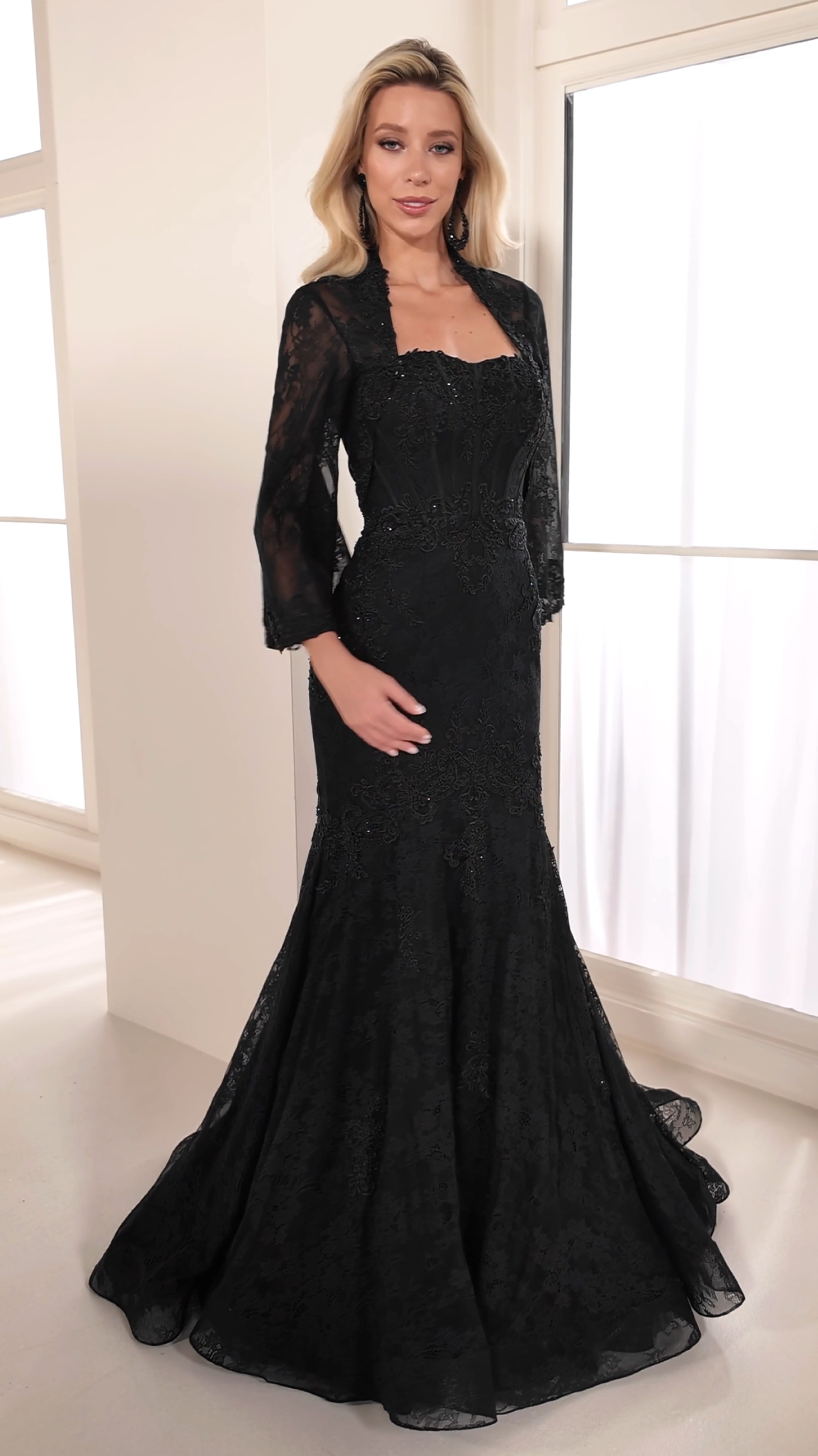 model is wearing a long sleeve black evening gown