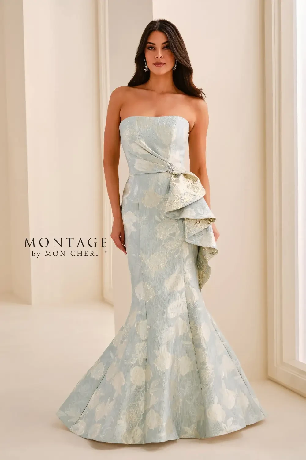 A woman wearing a strapless, light blue floral gown with a ruffled detail on the side.
