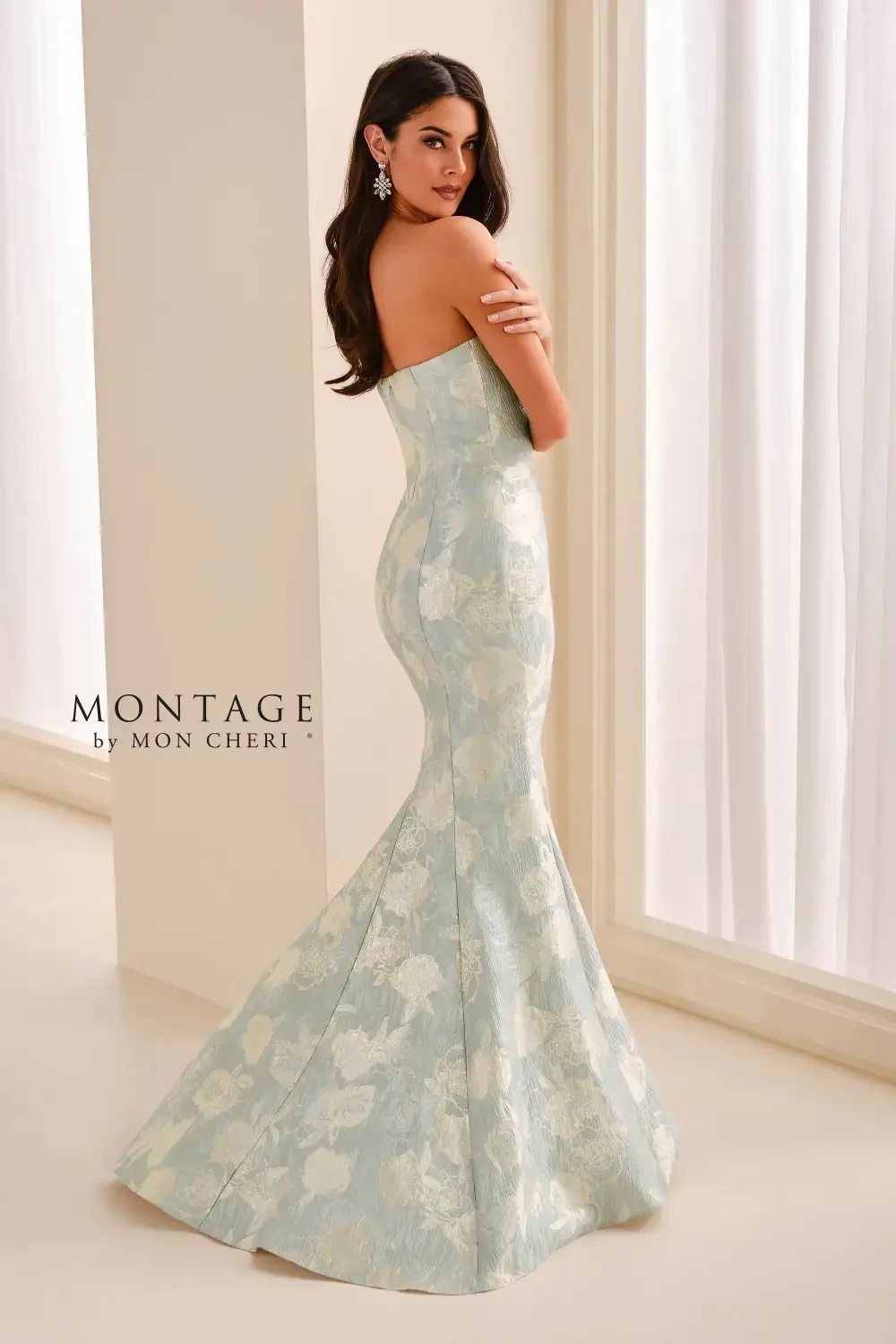A woman wearing a strapless, light blue floral gown with a ruffled detail on the side.