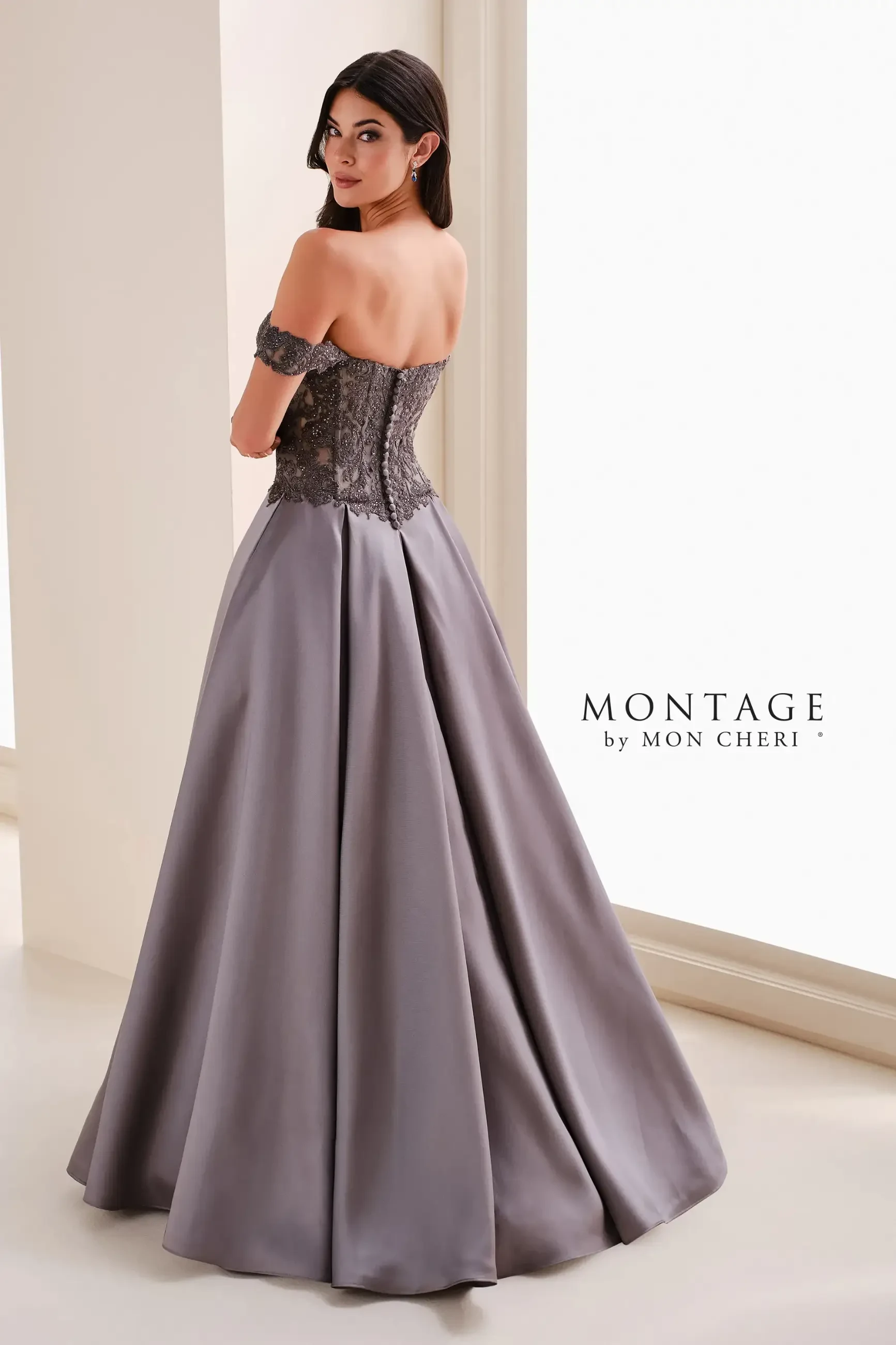 A woman in an elegant, off-the-shoulder gown with a beaded bodice and flowing lavender skirt stands by a window, exuding sophistication.