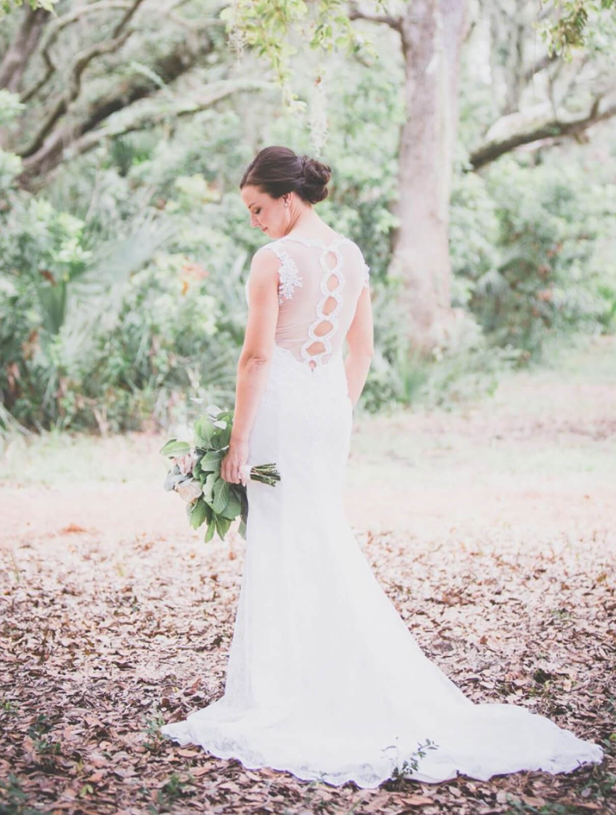 Brunette bride in field holding floral bouquet