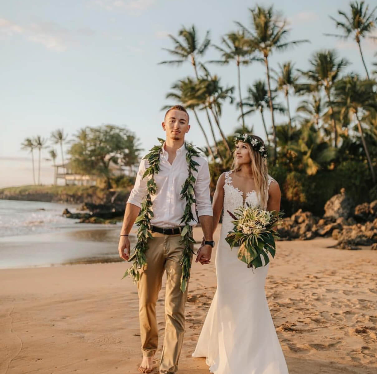 Bride and groom holding hands along the seaside