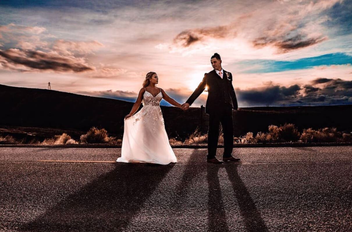 Bride and groom holding hands at sunset