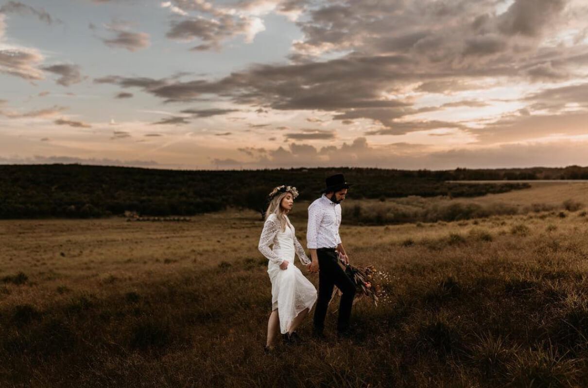 Bride and groom holding hands at sunset