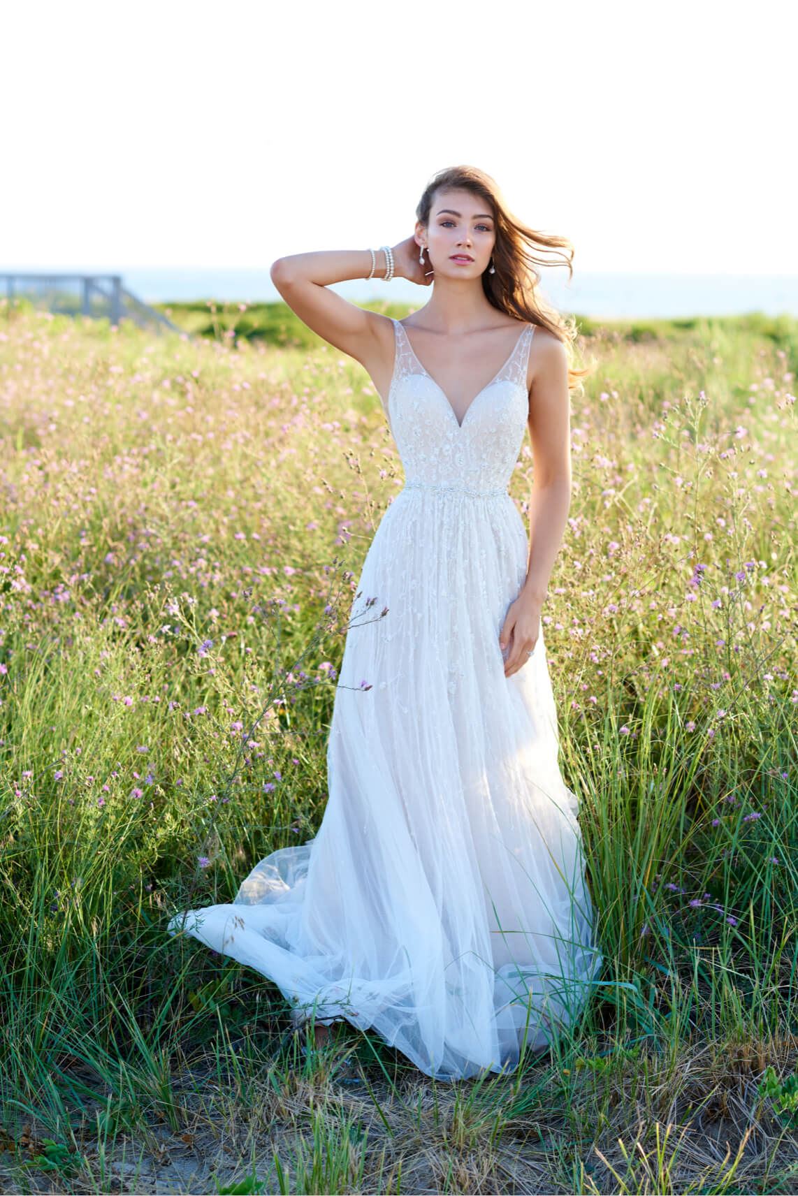 Brunette bride wearing white wedding dress on seashore