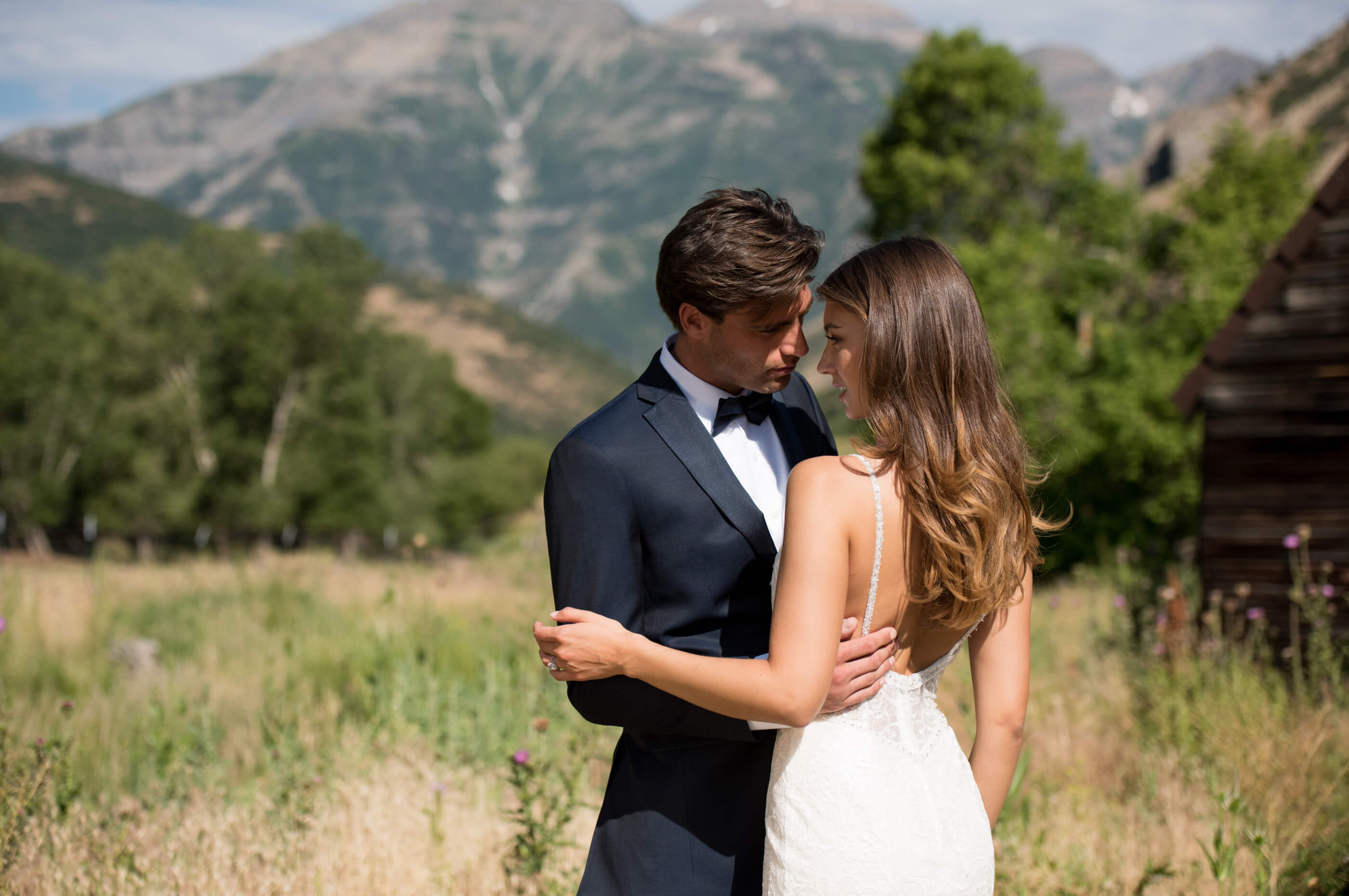 Brunette bride and groom standing in field holding each other